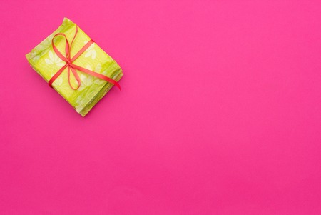 Pile with feminine sanitary pads tied with a red ribbon, pink background, copy space, regular, medicine, ovulationの写真素材