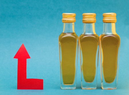 Small bottles with alcohol and a red arrow up concept of rising alcohol prices, extra charge, advanceの写真素材
