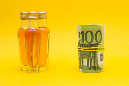 Small bottles with alcohol and euro money, income from the alcohol trade, price increase, close-up, buying alcohoの写真素材