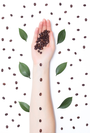 Contrast coffee beans, trendy handmade art, the hand of a girl on a white background with coffee petals, cosmeticの写真素材