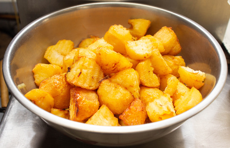Fried potatoes with a golden crust in a deep fryer, rustic slicesの写真素材