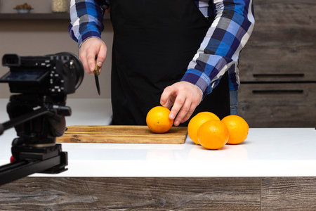 A man cuts fruit oranges on camera, online courses, blogger, cooking, close-up, homeの写真素材