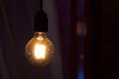 Incandescent bulb hanging in a night restaurant, copy space, filamentの写真素材