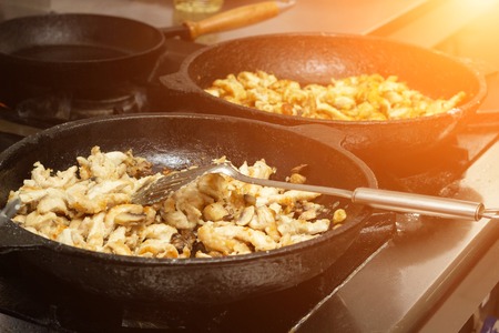 Two pans on which the chicken fillet roasts meat and mushrooms, restaurant, close-up, cookingの写真素材