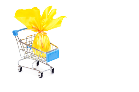 Yellow Easter egg in a shopping trolley on a white background, the concept of shopping and gifts for the holiday Easter, isolate, copy space, surpriseの写真素材
