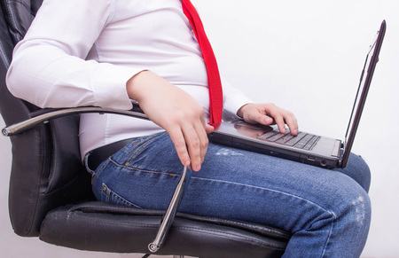 Office worker businessman with a laptop sitting on an office chair with a thick retractable stomach, bowel problems, gas, flatulence, bloatedの写真素材