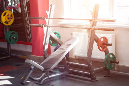 Sports bench with a barbell and discs on the rack to perform the barbell bench press in the modern gym, musculatureの写真素材