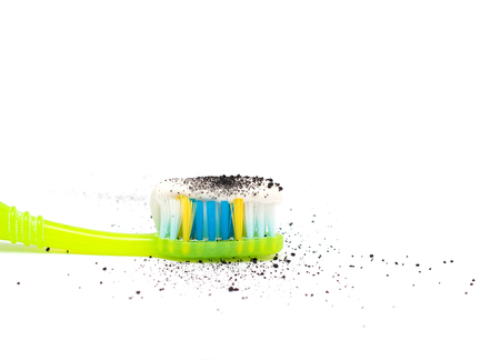 Toothpaste on a toothbrush with the addition of activated charcoal to better clean the teeth,...
