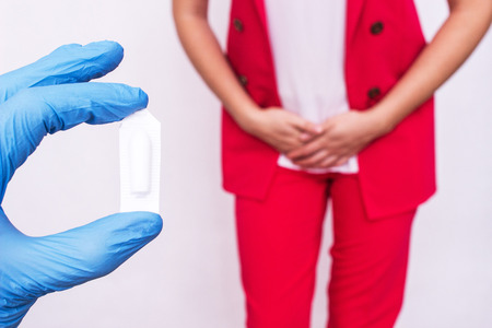 Doctor holds vaginal suppository suppository against the background of a girl who has pain and inflammation, urological infections, vaginal microflora, immunostimulatingの写真素材