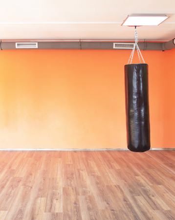 Boxing modern punching bag on the background of the orange wall in the new modern gym, copy space, powerの写真素材