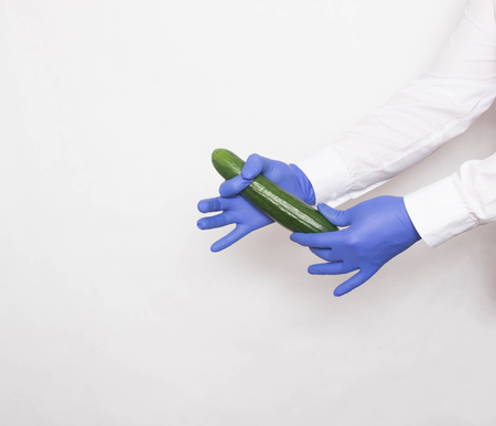 The doctor in medical gloves holds a cucumber in his hands, the concept of increasing the member...