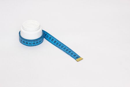 Cream on a white background with a measuring tape, the concept of increasing the member's...