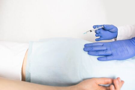 Doctor proctologist treats a patient for hemorrhoids with the help of modern method sclerotherapy, white background, copy spaceの写真素材