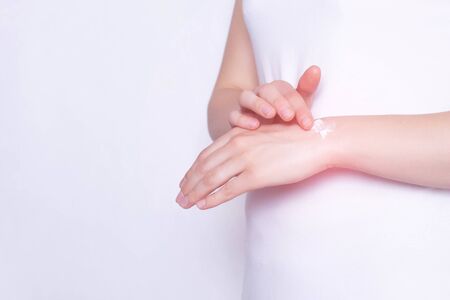 The girl rubs the healing ointment into the wrist joint against pain and inflammation in the joint, White background, copy spaceの写真素材