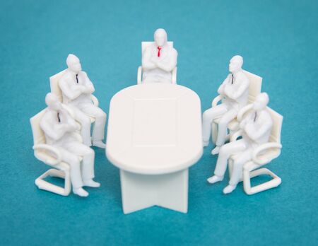 Toy people with ties are sitting at the same table. A concept of meeting managers and business people in the office, conferenceの写真素材
