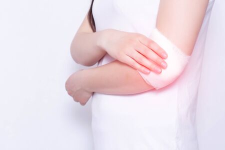 Medical compress on the elbow of the girl for pain and inflammation, white background, copy space, anesthesia, dislocationの写真素材