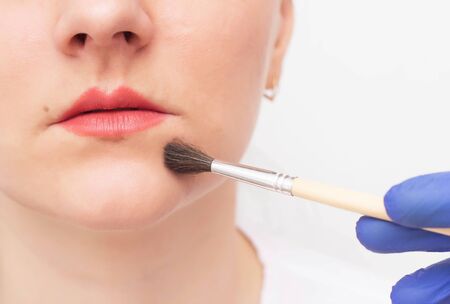 Doctor cosmetologist conducts chemical peeling for a girl to increase lips, tattoo, medicineの写真素材
