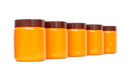 Orange plastic jars with a brown lid on a white background, isolateの写真素材