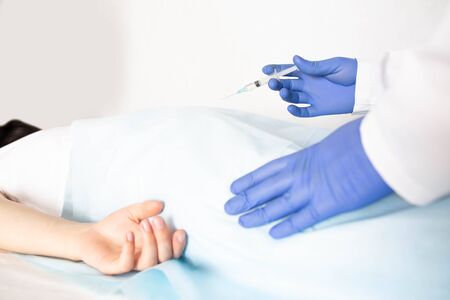 Doctor proctologist treats a patient for hemorrhoids with the help of modern method sclerotherapy, white background, copy space, blood supplyの写真素材