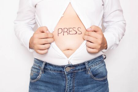 A man holds a shirt open with a bare stomach on which the word press is written, obesity concept and sports, fattyの写真素材