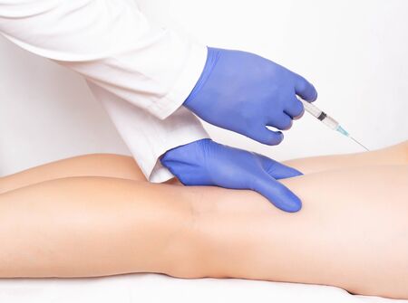 Doctor cosmetologist makes rejuvenation beauty injection to the back of the feet to smooth out...