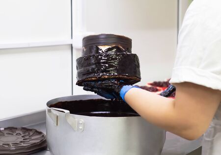 the confectioner makes a chocolate cake, pours chocolate on the biscuit cakes, handmade. Cake Making, torte, beautifulの写真素材