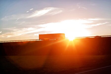 Modern wagon truck transports cargo against the backdrop of a sunset. The concept of truck drivers in the field of freight and logistics, copy spaceの写真素材