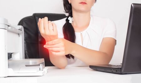 Young caucasian girl office worker holds on wrist joint pain and inflammation concept in hand, tunnel syndrome, orthopedicの写真素材