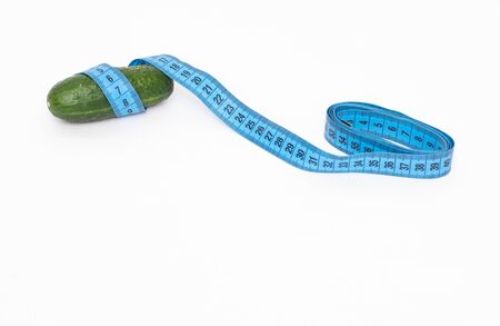 Cucumber wrapped with a measuring tape on a white background, concept of penis size in men, penis enlargement, copy space, measurementの写真素材