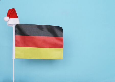 Flag of Germany with little santa claus hat on blue background. New Year winter holiday concept, copy space, beautifulの写真素材