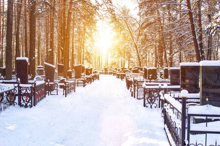 Winter cemetery in the background of the sun, alley. Copy space, graveyard