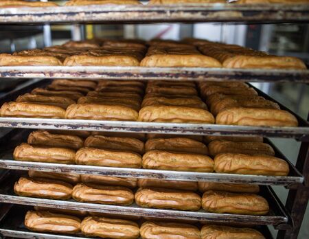 Many custard eclair cakes with butter cream and condensed milk lie on racks in the confectionery...