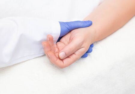 The doctor probes the pulse of an elderly woman on her wrist. Heart disease concept and symptoms of diseases recognizable by pulse, blood loss, close-up, backgroundの写真素材