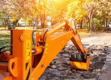 An excavator's rear bucket digs in the courtyard of a residential building. Replacement of heating main and pipes for water, industryの写真素材