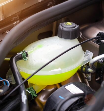 Car reservoir for filling coolant. Yellow antifreeze in the expansion tank, freezing temperature...