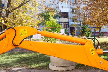 Yellow excavator bucket on the background of a residential building in the yard. The concept of the...