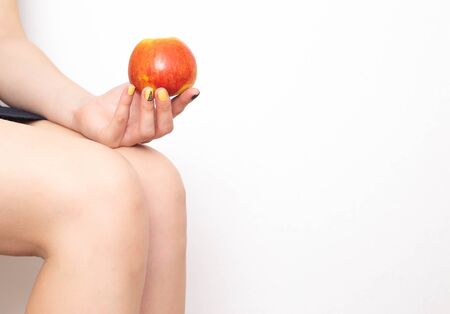 Girl holds an apple on a background of knees. Healthy eating concept for joints. Joint Health Dietの写真素材