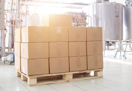 Boxes with finished dairy products at the factory on the background of production equipment. The concept of the production of milk and sour cream, the manufacture of glazed curds and butterの写真素材