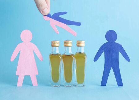 Wooden figures with bottles of alcohol on a blue background. Family Alcoholism Treatment Conceptの写真素材