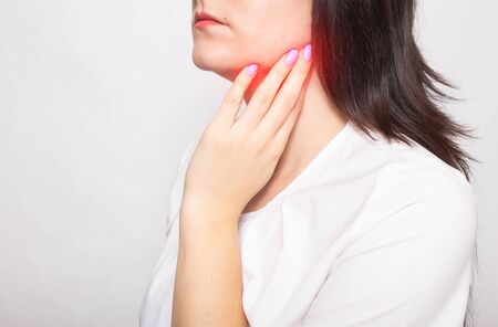 The girl clings to the inflamed salivary gland in which pain. Concept of salivary gland disease, mumps, cancer, copy space, retention cystの写真素材