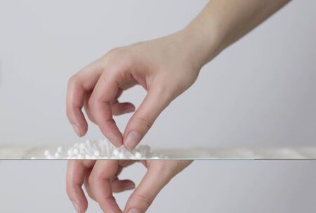 Girl takes an absorbent cotton swab from the table for skin and ear care, backgroundの写真素材