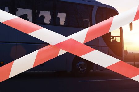 Forbidden tape on the background of a travel company passenger bus. The concept of loss and closure of tour operators during the coronavirus pandemic, bankrupt. Closing state borders, traveling COVID-19の写真素材