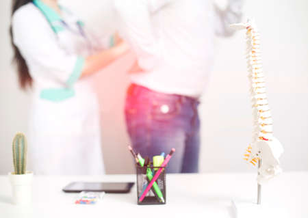 Male patient at the appointment with a doctor vertebrologist. Diagnosis and treatment of back pain diseases, background. Dislocation and trauma of the intervertebral disc, pinched nerve, spinal deformitiesの写真素材