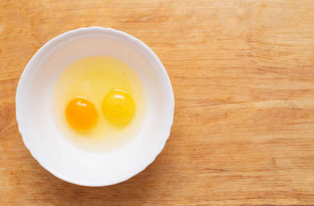 Two chicken eggs, homemade and factory, are broken in a glass plate. Difference concept of homemade natural eggs from store-bought, organicの写真素材