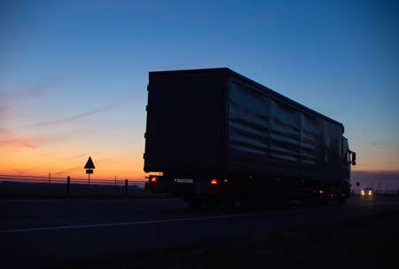 a cargo truck drive on the motorway in the evening against the backdrop of sunset. Truck logistics...