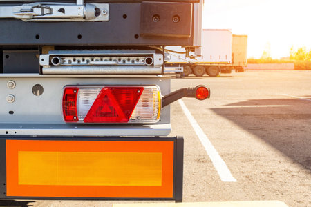 Truck driver semitrailer rear view, warning lights and long length signs on the trailer. Concept of safety and recreation at truck parking lots, sunset, copy space for text, industrialの写真素材