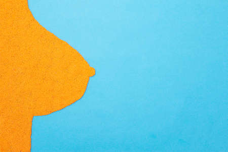 Plasticine female breast on a blue background. Female breast augmentation concept, plastic surgery,...
