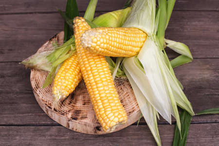 Natural cob of corn in husks on a wooden background. The concept of natural vegetables grown in...