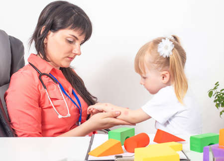 An allergist doctor examines the hand of a little girl for allergies. The concept of allergy to insect bites, dust and medications, caucasian, chemical substancesの写真素材