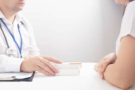 The doctor holds out medicines to the patient in the doctor's office. Concept for the sale of homeopathic medicines and biologically active food supplements. Anologist of expensive drugs, painkillersの写真素材